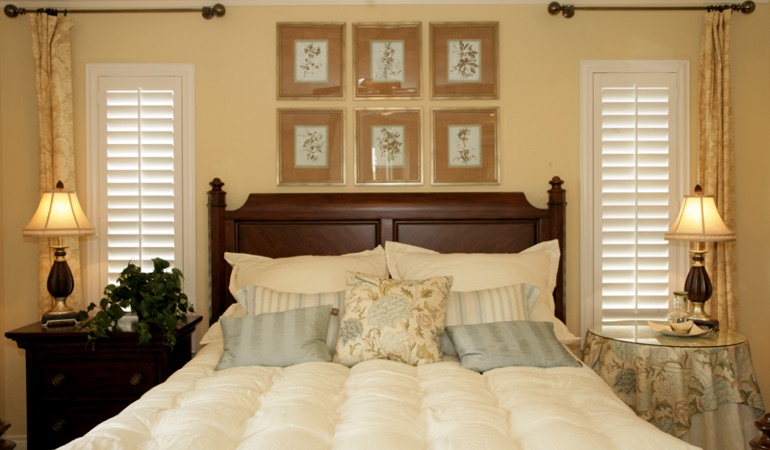 Tall plantation shutters framing bed in a bedroom in Indianapolis 